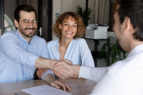 Stretta di mano tra agente e clienti soddisfatti nel marketing immobiliare di successo