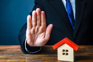 mano che rifiuta una casa simbolo di venditore che scarta l’agente immobiliare