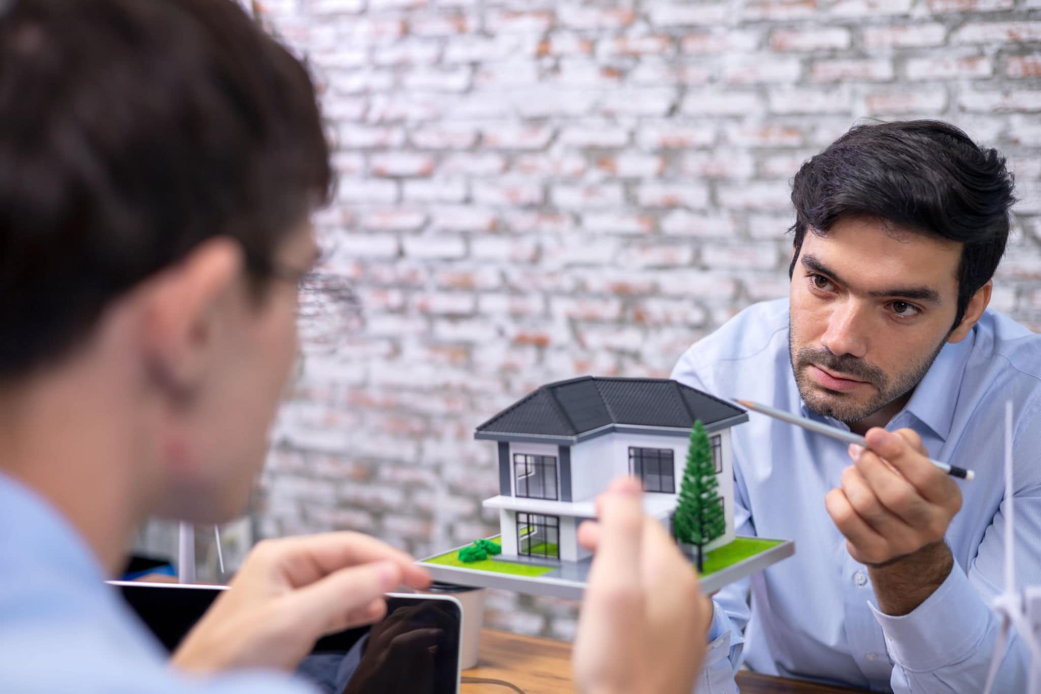 venditore che mostra esitazione mentre ascolta l’agente immobiliare durante l’incontro