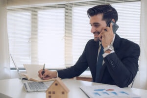 telefonate da agenzie immobiliari: agente al telefono mentre lavora al laptop e gestisce la chiamata con approccio di qualifica